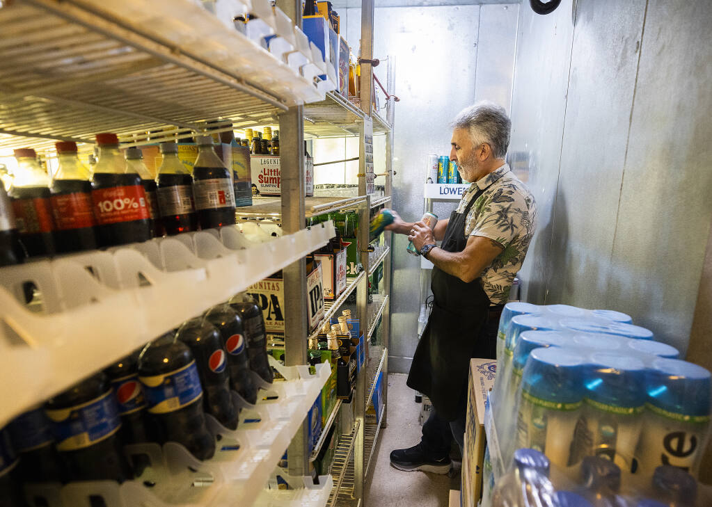 Neil Mogannam, owner of the 4th Street Deli in Santa Rosa, restocks the drinks in his walk-in cooler September 22, 2022. Mogannam, who says refrigeration is the highest cost on his utility bill, had his largest electricity bill ever due to usage during the recent extreme heat. (John Burgess/The Press Democrat)