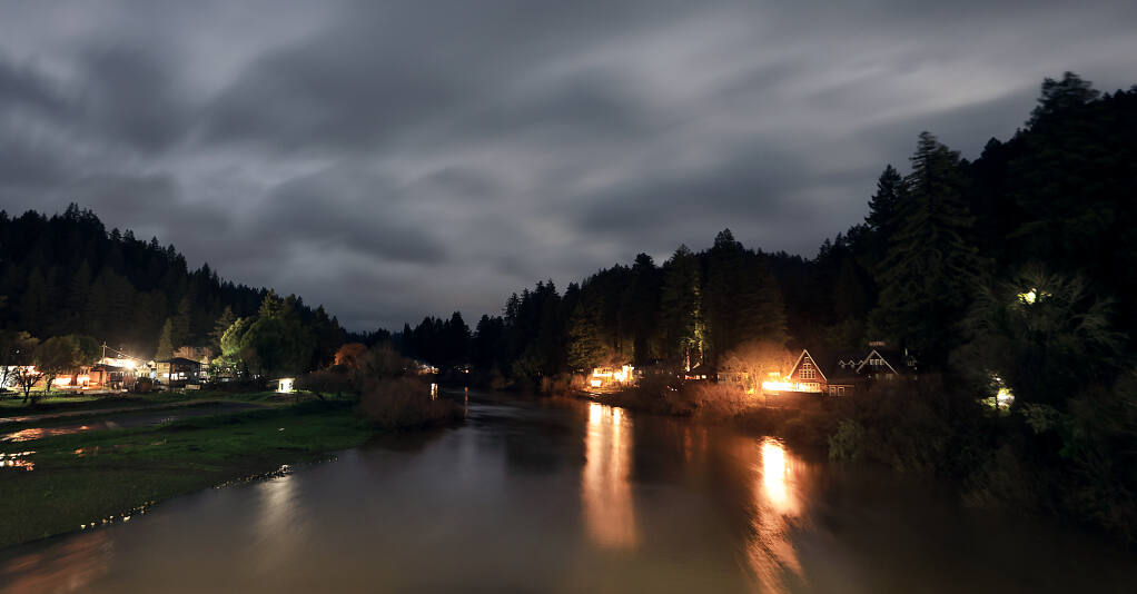 Storm clouds from Wednesday's landfall of a major winter storm begin to part, lit by the moon, as the Russian River at Monte Rio slowly rises Wednesday evening. (Kent Porter / The Press Democrat) 2023