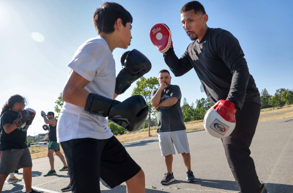 Rosendo Sanchez, center, owner of Sanchez Boxing Gym, watches Tony Perez, right, work with Adriell Bermudez, 15, during a workout at Southwest Community Park in Santa Rosa on Thursday, June 29, 2023. (Christopher Chung/The Press Democrat)
