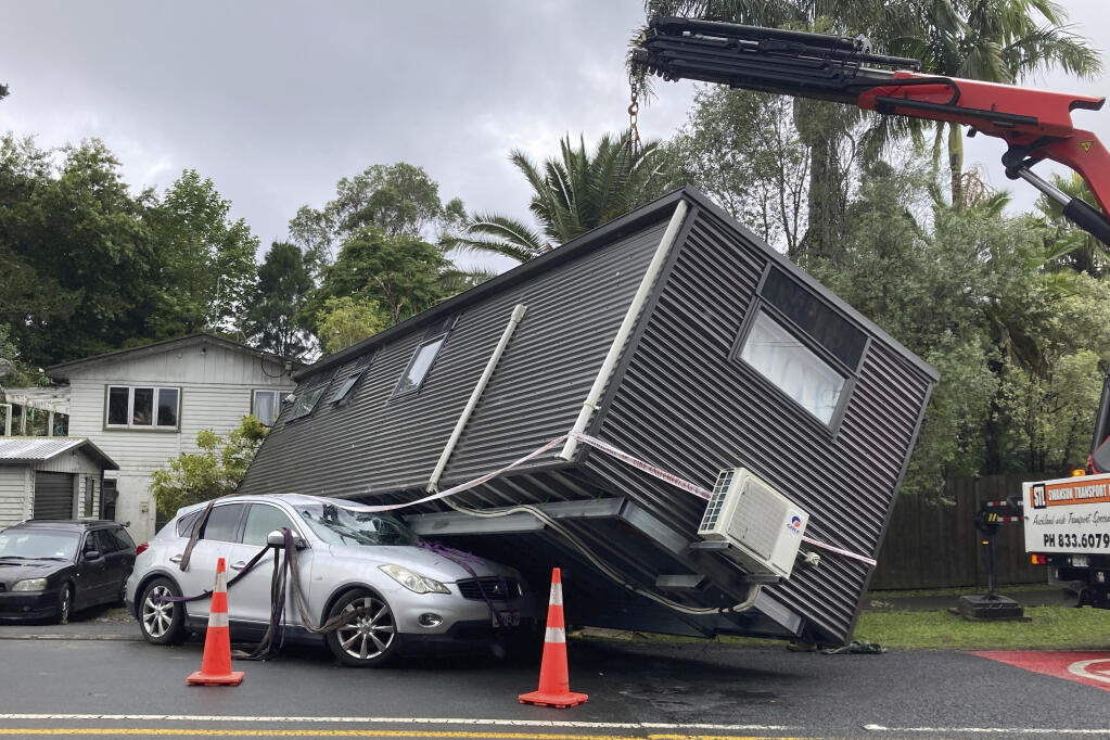 A portable building rests on a car after flood water shifted the structure in Auckland, Saturday, Jan. 28, 2023. Record levels of rainfall pounded New Zealand's largest city, causing widespread disruption. (Elizabeth Binning/New Zealand Herald via AP)