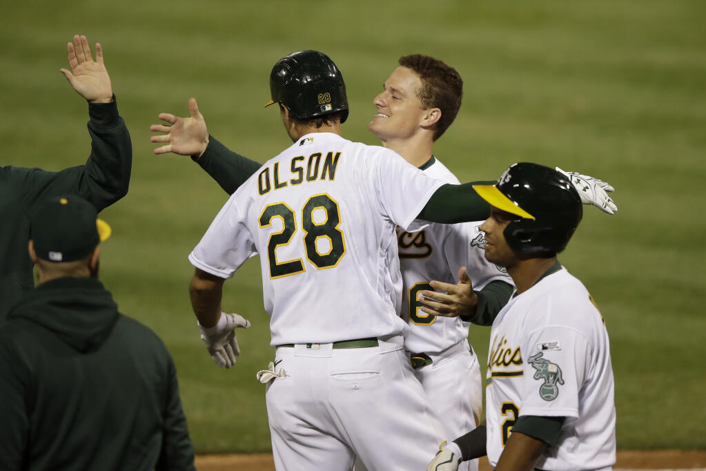 Oakland Athletics' Matt Olson (28) celebrates with Matt Chapman after hitting a grand slam home run against the Los Angeles Angels in the tenth inning of a baseball game in Oakland, Calif., Friday, July 24, 2020. (AP Photo/Jeff Chiu)