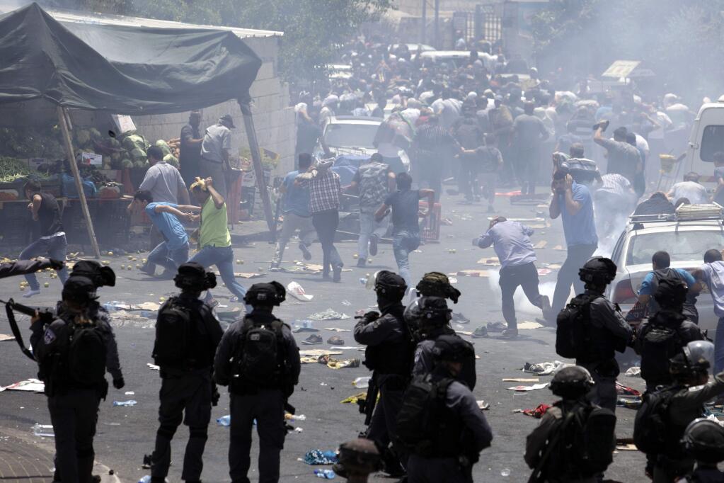 Palestinians run away from tear gas in Jerusalem, Friday, July 21, 2017. An escalating dispute over metal detectors at a contested Jerusalem shrine turned violent on Friday, setting off widespread clashes between Palestinian stone-throwers and Israeli troops. (AP Photo/Mahmoud Illean)