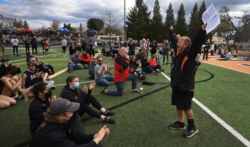 Long time Santa Rosa High School track and field coach Doung Courtemarche, 74, who officially retired after the 2019 track season, leads a cheer of past and present athletes that he coached, Saturday, March 5, 2022, during a ceremony to name the field after him during the Big Cat Invittational. (Kent Porter / The Press Democrat) 2022