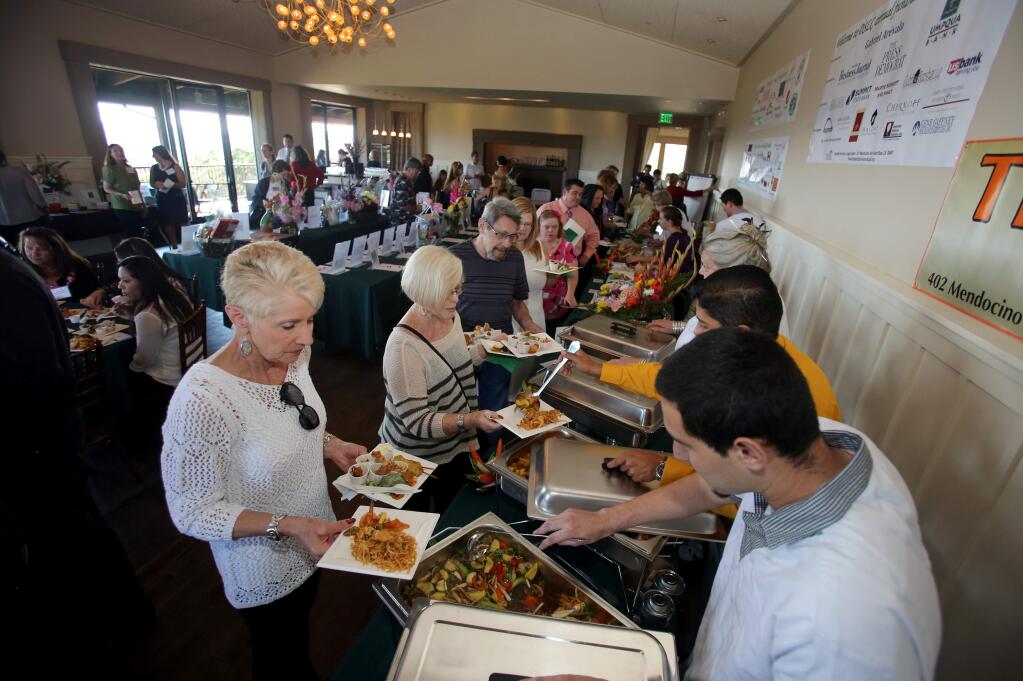 Gloria Frere, left, waits as Andres Arevalo, right, of Thai Time Asian Bistro dishes food during the 'Music in the Vines' at Paradise Ridge Winery, in Santa Rosa, Thursday, June 26, 2014. The event was a benefit of Disability Services & Legal Center. (Crista Jeremiason / The Press Democrat)