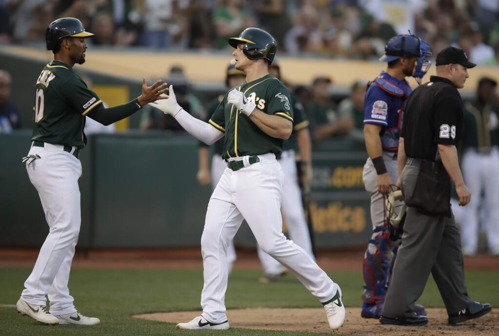The Oakland Athletics' Matt Chapman, center, celebrates with Marcus Semien, left, after hitting a two-run home run off the Texas Rangers' Adrian Sampson in the fifth inning, Saturday, July 27, 2019, in Oakland. (AP Photo/Ben Margot)