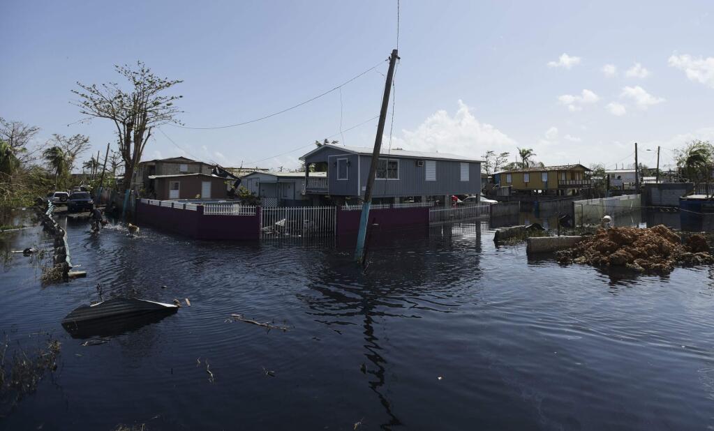 Homes in the Juana Matos community are surrounded by flood waters in Catano, Puerto Rico, Thursday, Sept. 28, 2017, one week after the passage of Hurricane Maria. (AP Photo/Carlos Giusti)
