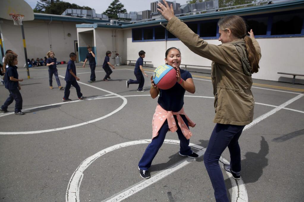 Sixth grader Ximena Becerra, 11, tries to pass the ball around seventh grader Tessa Devine, 12, during recess at Santa Rosa French American Charter School in Santa Rosa, on Thursday, April 7, 2016. (BETH SCHLANKER/ The Press Democrat)