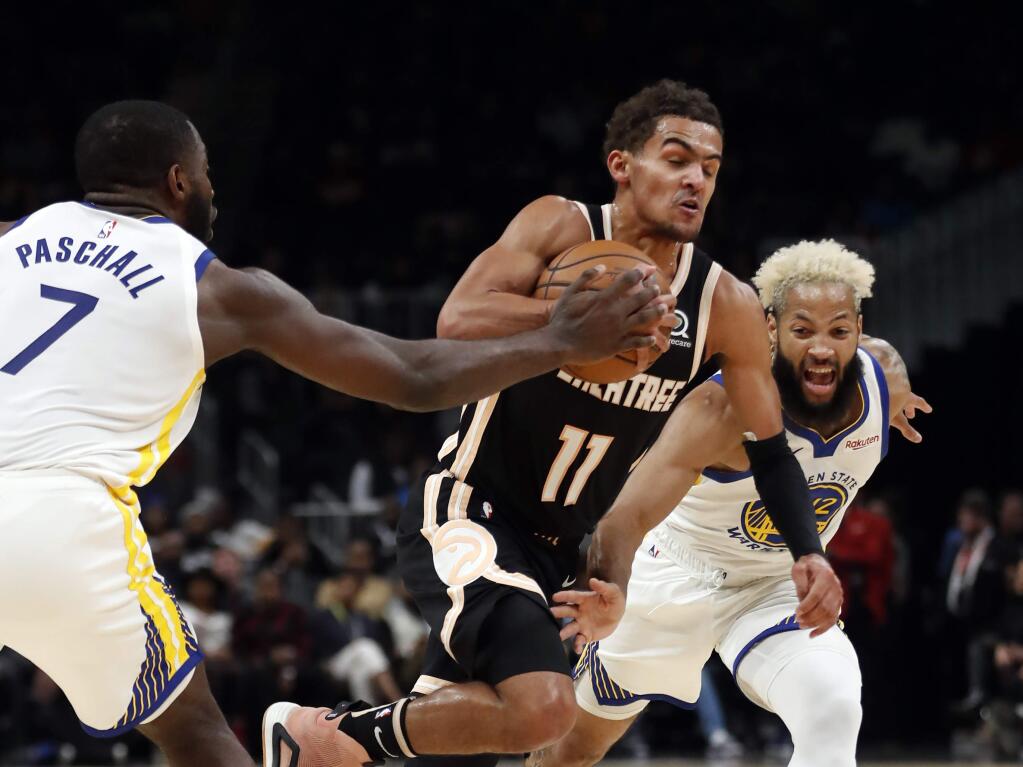 Atlanta Hawks guard Trae Young (11) drives between Golden State Warriors' Eric Paschall (7) and Ky Bowman (12) in the first half of an NBA basketball game Monday, Dec. 2, 2019, in Atlanta. (AP Photo/John Bazemore)