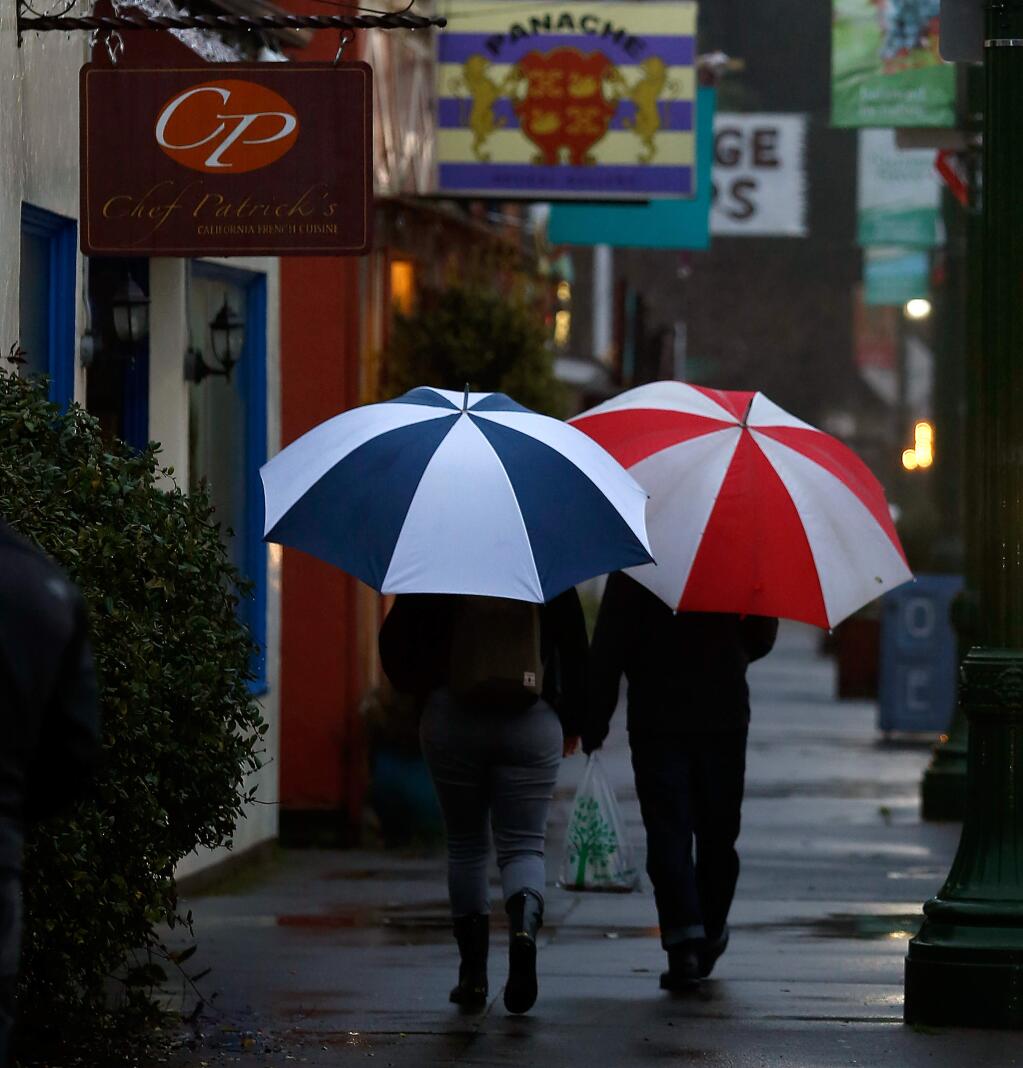 A couple with colorful umbrellas takes a walk through downtown Guerneville, California on Saturday, Jan. 7, 2017. (Alvin Jornada / The Press Democrat)