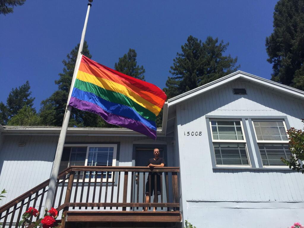 Guerneville resident Dustin Coupe lowered his pride flag to half-staff on Sunday, June 12, 2016, in mourning for victims of a mass shooting at a gay nightclub in Orlando, Florida. ( BETH SCHLANKER / Press Democrat )
