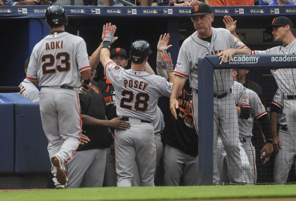 San Francisco Giants' Buster Posey (28) is congratulated as he comes into the dugout along with Nori Aoki (23) after hitting a two-run home run against the Atlanta Braves during the third inning of a baseball game, Monday, August 3, 2015, in Atlanta. (AP Photo/John Amis)