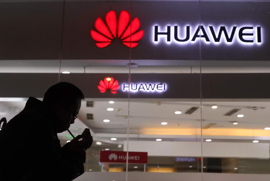 A man lights a cigarette outside a Huawei retail shop in Beijing Thursday, Dec. 6, 2018. China on Thursday demanded Canada release a Huawei Technologies executive who was arrested in a case that adds to technology tensions with Washington and threatens to complicate trade talks. (AP Photo/Ng Han Guan)