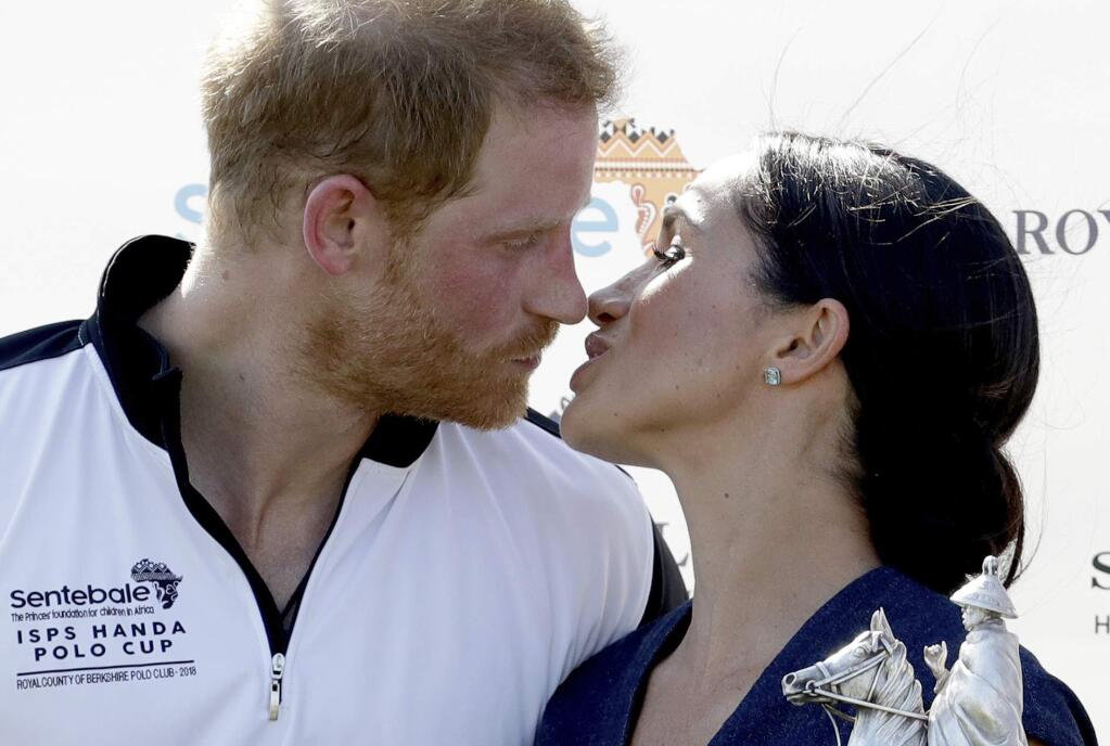FILE - In this file photo dated Thursday, July 26, 2018, Meghan, Duchess of Sussex and Britain's Prince Harry kiss during the presentation ceremony for the Sentebale ISPS Handa Polo Cup, at the Royal County of Berkshire Polo Club in Windsor, England. Kensington Palace announced Monday Oct. 15, 2018, that Prince Harry and his wife the Duchess of Sussex are expecting a child in the spring 2019.(AP Photo/Matt Dunham, FILE)
