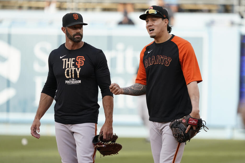 San Francisco Giants manager Gabe Kapler, left, talks with third baseman Wilmer Flores, right, during batting practice before Game 3 of a baseball National League Division Series against the Los Angeles Dodgers, Monday, Oct. 11, 2021, in Los Angeles. (AP Photo/Marcio Sanchez)