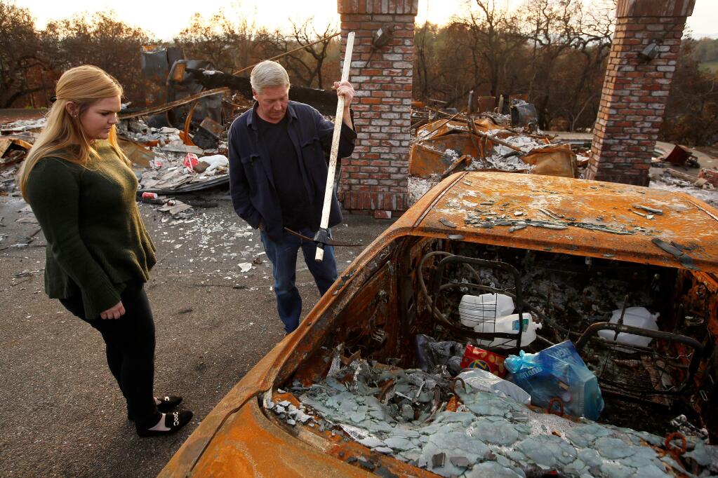 Roger Anderson and his daughter Kristina find an improvised pickaxe fashioned from PVC pipe along with bags of trash, left inside what was once their family's car at their Southridge Drive home that was destroyed by the Tubbs Fire, in the Fountaingrove neighborhood of Santa Rosa, California on Friday, December 29, 2017. The Andersons returned to their burned Fountaingrove lot on Christmas Eve to hang holiday decorations, only to finde several bags of trash, as well as alcohol bottles and cans strewn around their former home. (Alvin Jornada / The Press Democrat)