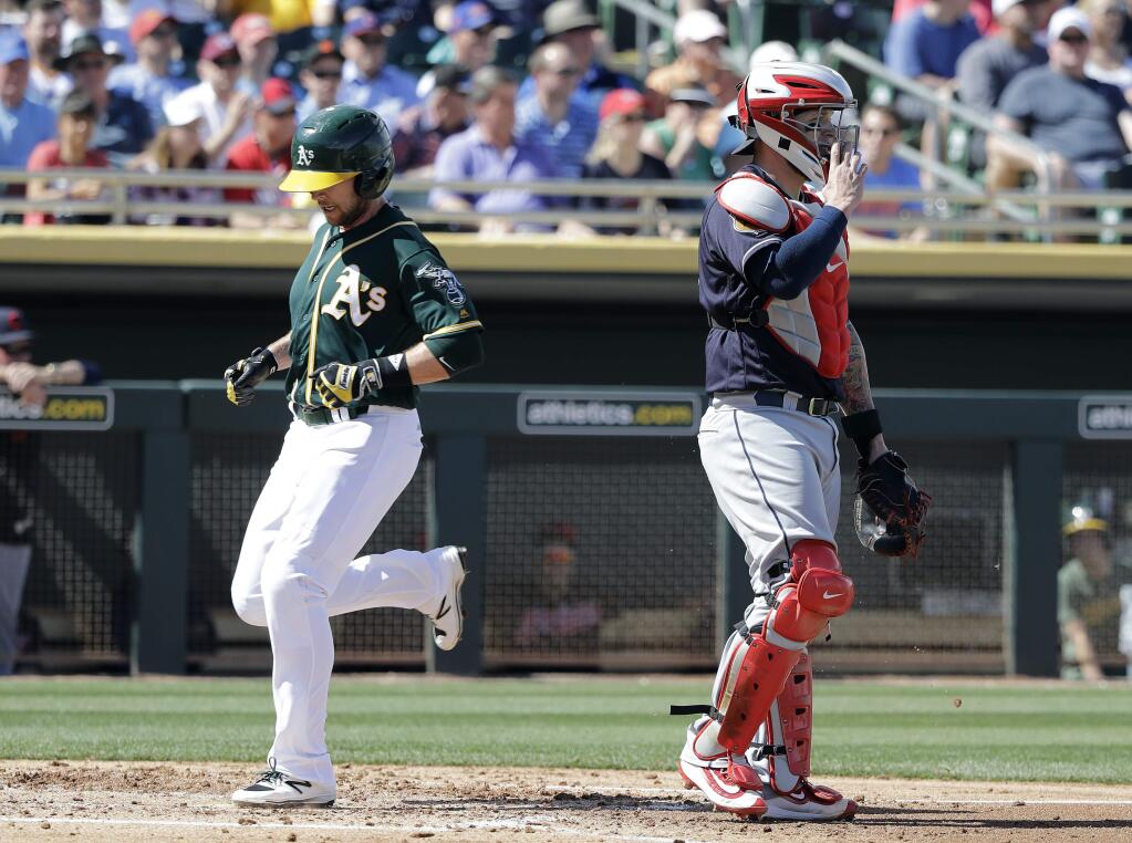 Oakland Athletics' Jed Lowrie scores as Cleveland Indians catcher Roberto Perez watches during the first inning of a spring training baseball game Saturday, March 4, 2017, in Mesa, Ariz. (AP Photo/Darron Cummings)