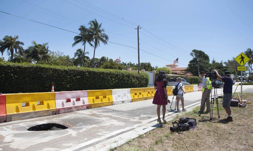 A TV crew reports next to a recently opened sinkhole near President Donald Trump's Mar-a-Lago estate, Monday, May 22, 2017 in Palm Beach, Fla. The 4-foot-by-4-foot hole was discovered Monday. It is near a new water drain and isn't a threat to the president's property. (Meghan McCarthy/Daily News via AP)