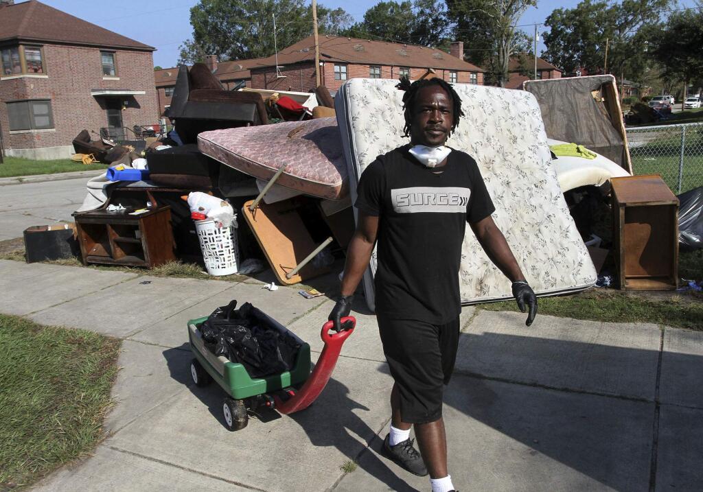 Volunteer Johnnie Evans brings a wagon of water to cleanup crews helping with the grisly task of removing storm damaged belongings, spoiled food and soaked furniture at Trent Court Apartments in New Bern, N.C., Sept. 21, 2018. Hurricane Florence brought storm surges which overflowed from the Trent River and forced many residents of Trent Court to evacuate. (Gray Whitley / Sun Journal via AP)