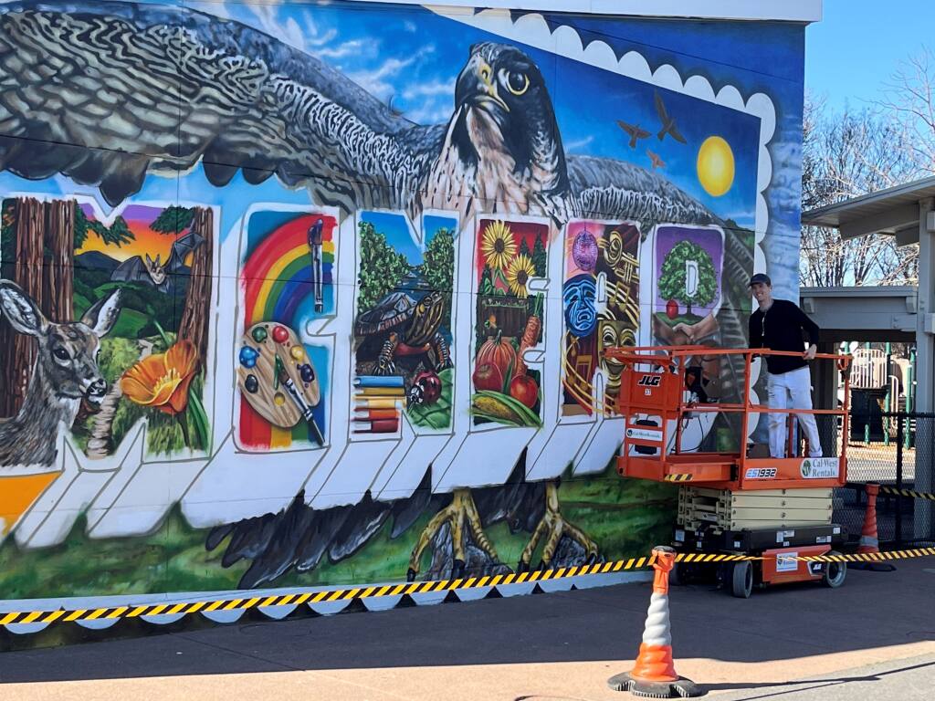 Maxfield Bala (far right, on lift), on Friday, Feb. 10, 2023, working on the mural at McNear Elementary School, which he began painting on Monday. (David Templeton/Argus-Courier Staff)