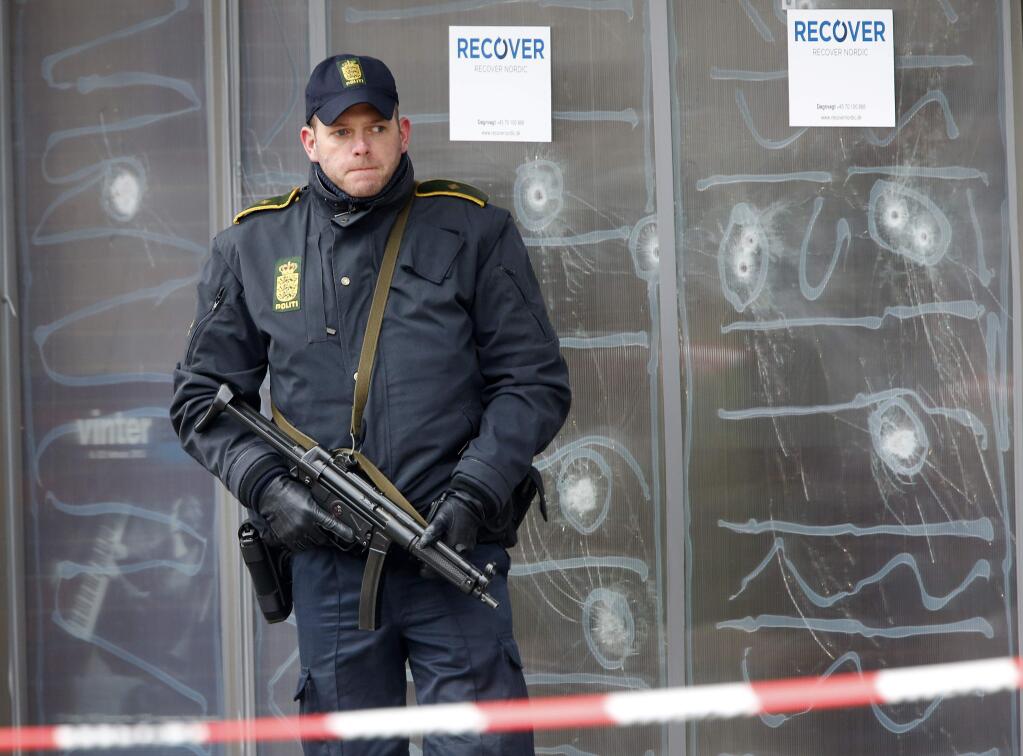 A police officer stands guard in front of a cultural center where an alleged shooter killed one person on Saturday in Copenhagen, Denmark, Monday, Feb. 16, 2015. The shooter was killed by police who believe he also shot a second person at the Jewish synagogue. (AP Photo/Michael Probst)