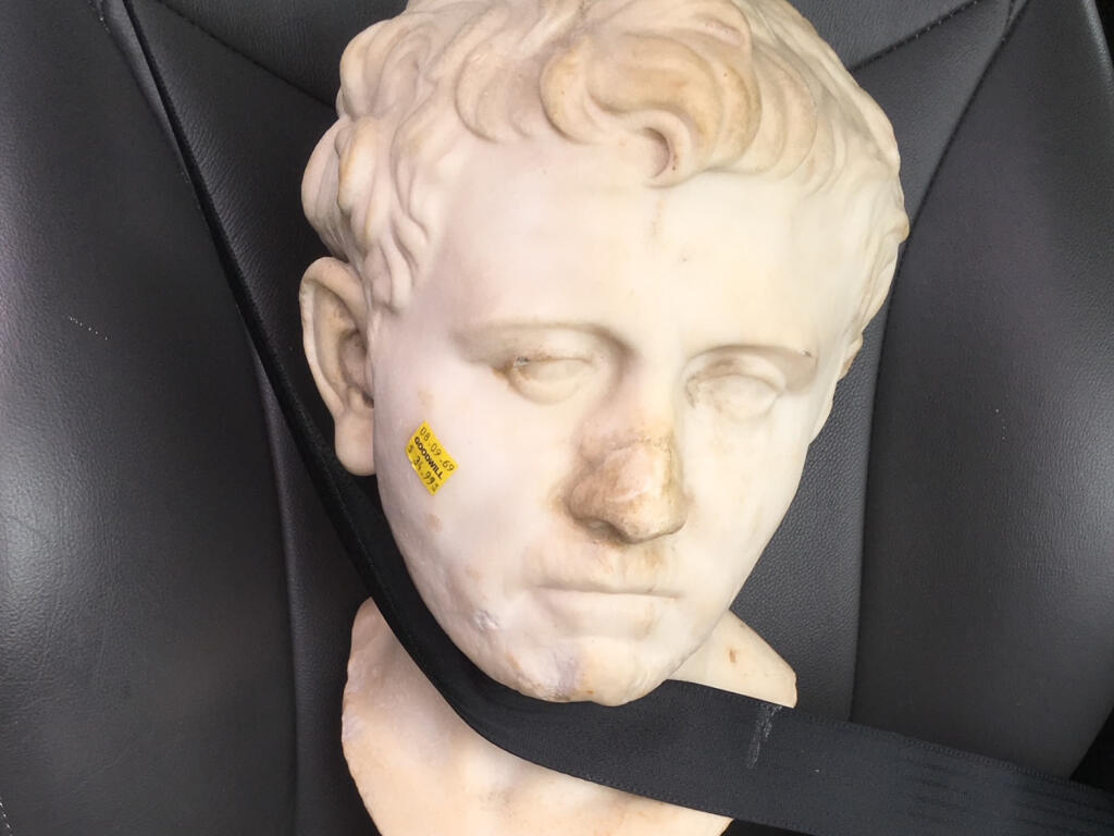 An undated photo by Laura Young shows the ancient Roman bust that she found at a Goodwill store in Austin, Texas, with a $34.99 price tag still on it’s cheek and strapped into a car seat, on the day she bought it and took it home. The relic’s 2,000-year journey to Texas remains a mystery, but the buyer is returning it to the German state of Bavaria, its pre-World War II home. (Laura Young via The New York Times)