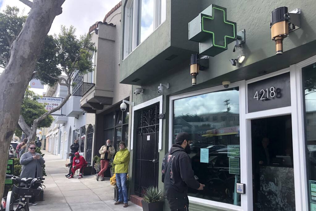 Customers maintain social distance while waiting to enter The Green Cross cannabis dispensary in San Francisco, Wednesday, March 18, 2020. As about 7 million people in the San Francisco Bay Area are under shelter-in-place orders, only allowed to leave their homes for crucial needs in an attempt to slow virus spread, marijuana stores remain open and are being considered 'essential services.' (AP Photo/Haven Daley)