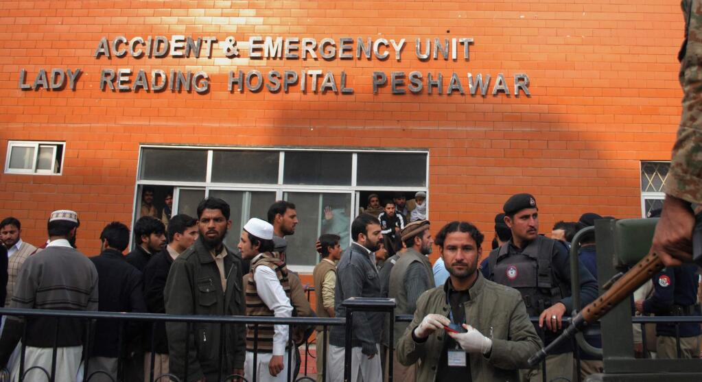 People gather at a hospital, where victims of a Taliban attack are being treated in Peshawar, Pakistan, Tuesday, Dec. 16, 2014. Taliban gunmen stormed a military-run school in the northwestern Pakistani city of Peshawar on Tuesday, killing and wounding scores, officials said, in the highest-profile militant attack to hit the troubled region in months.(AP Photo/Mohammad Sajjad)