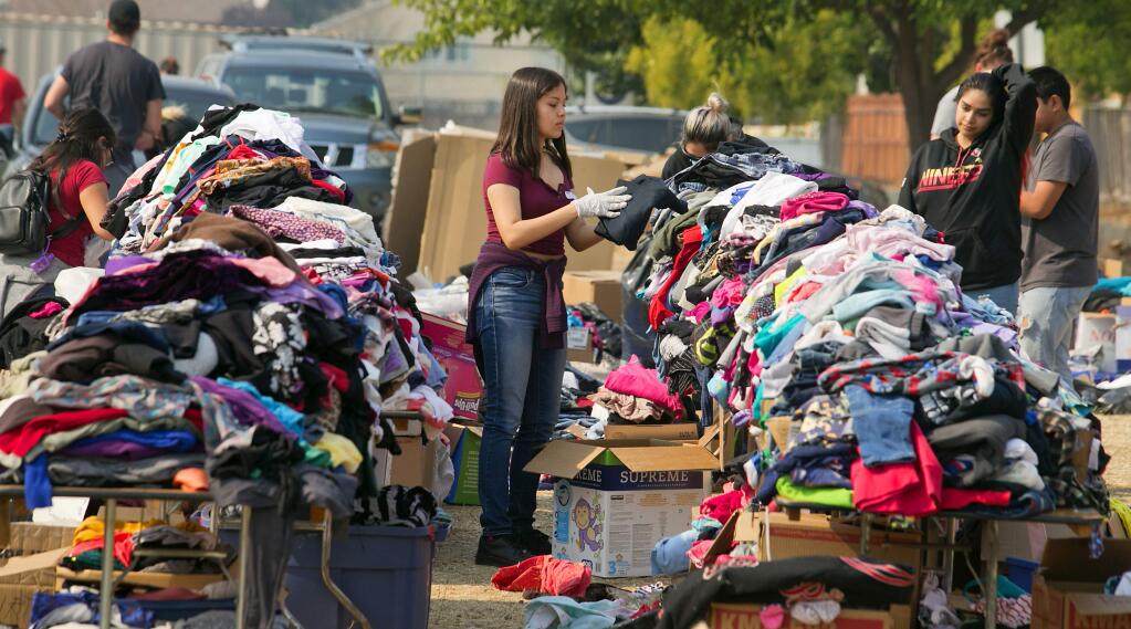 Volunteer Jasmine Flores sorts through thousands of donated items for fire evacuees at Elsie Allen High School in Santa Rosa on October 13, 2017. (photo by John Burgess/The Press Democrat)