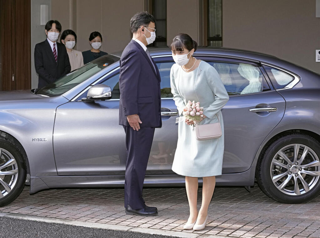 Japan's Princess Mako bows before leaving her home in Akasaka Estate in Tokyo Tuesday, Oct. 26, 2021. Mako and her commoner boyfriend Kei Komuro tied the knot Tuesday without wedding celebration in a marriage that has split the public opinion over her would-be mother-in-law’s financial controversy. Standing in the background are from left, her parents Crown Prince Akishino, Crown Princess Kiko and her sister Princess Kako. (Koki Sengoku/Kyodo News via AP)