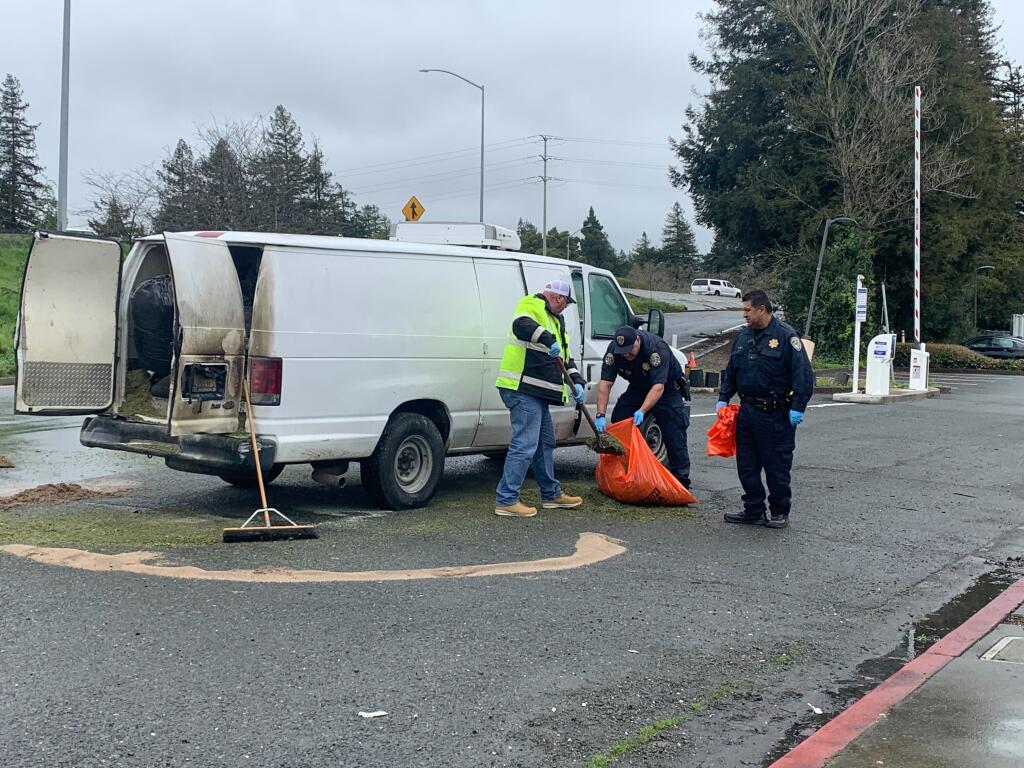A marijuana spill is cleaned up by Santa Rosa police officers and road crew on Davis  and 3rd streets in downtown Santa Rosa, Tuesday, March 14, 2023. The spill forced the shutdown of the Highway 101 on-ramp nearby. (The Press Democrat)