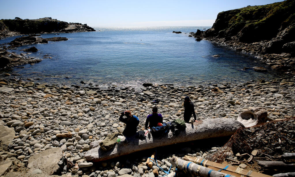 Chelsea Furr, 13, and her father Dan Furr with Eddie Kennedy of Woodland, relax after snorkeling in Gerstle Cove on the Sonoma coast at Salt Point, Saturday, March 13, 2021. Very little bull kelp remains in the cove,  (Kent Porter / The Press Democrat) 2021