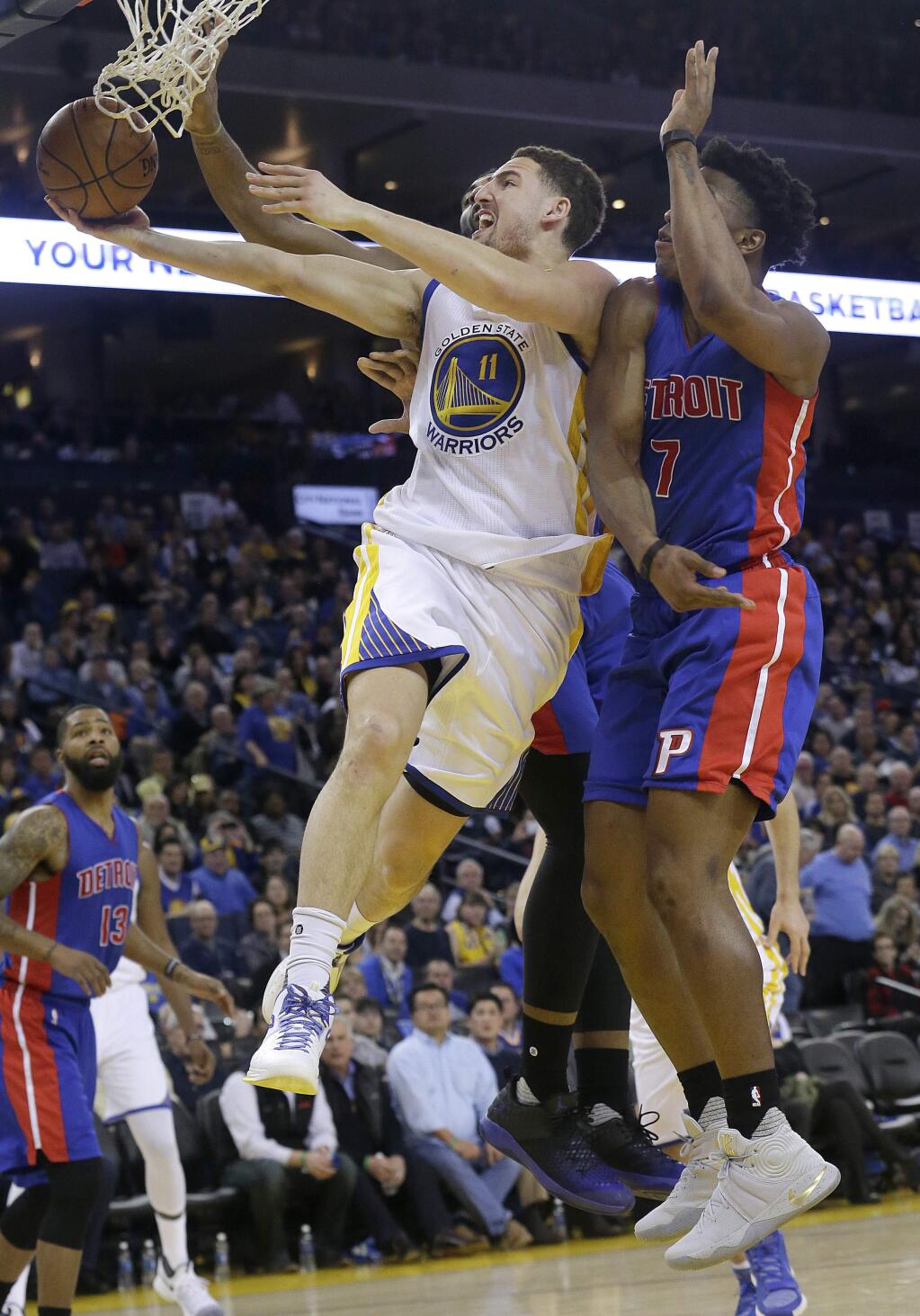 Golden State Warriors guard Klay Thompson (11) is fouled as he shoots against Detroit Pistons forward Stanley Johnson (7) and center Andre Drummond, rear, during the second half of an NBA basketball game in Oakland, Calif., Thursday, Jan. 12, 2017. (AP Photo/Jeff Chiu)