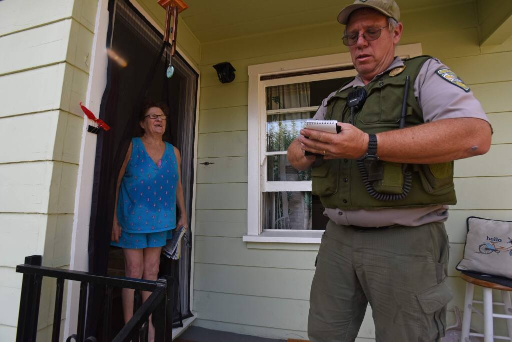 “I'm staying with my friend and kitty named Lily,” said Dana Cavallo, left, who refused to leave her home on University Avenue and defy a mandatory evacuation order as Bill Trunick, right, of the Sonoma County Regional Parks makes note of her refusal as he goes door to door Saturday in Healdsburg, California. October 26, 2019.(Photo: Erik Castro/for The Press Democrat)