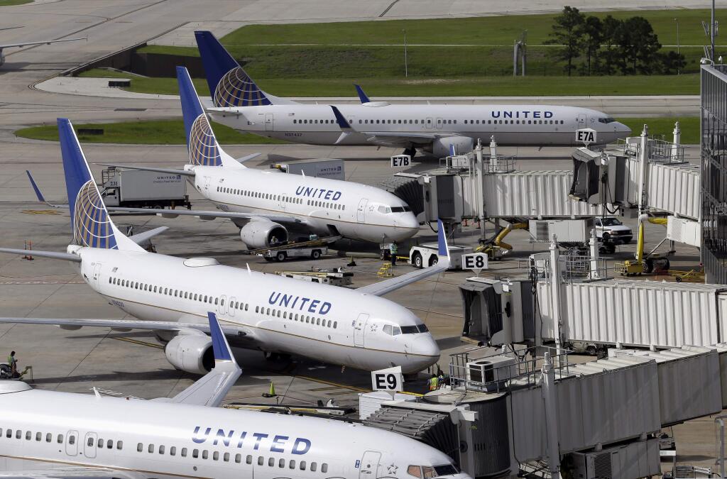 FILE - In this July 8, 2015, file photo, United Airlines planes are parked at their gates as another plane, top, taxis past them at George Bush Intercontinental Airport in Houston. (AP Photo/David J. Phillip, File)