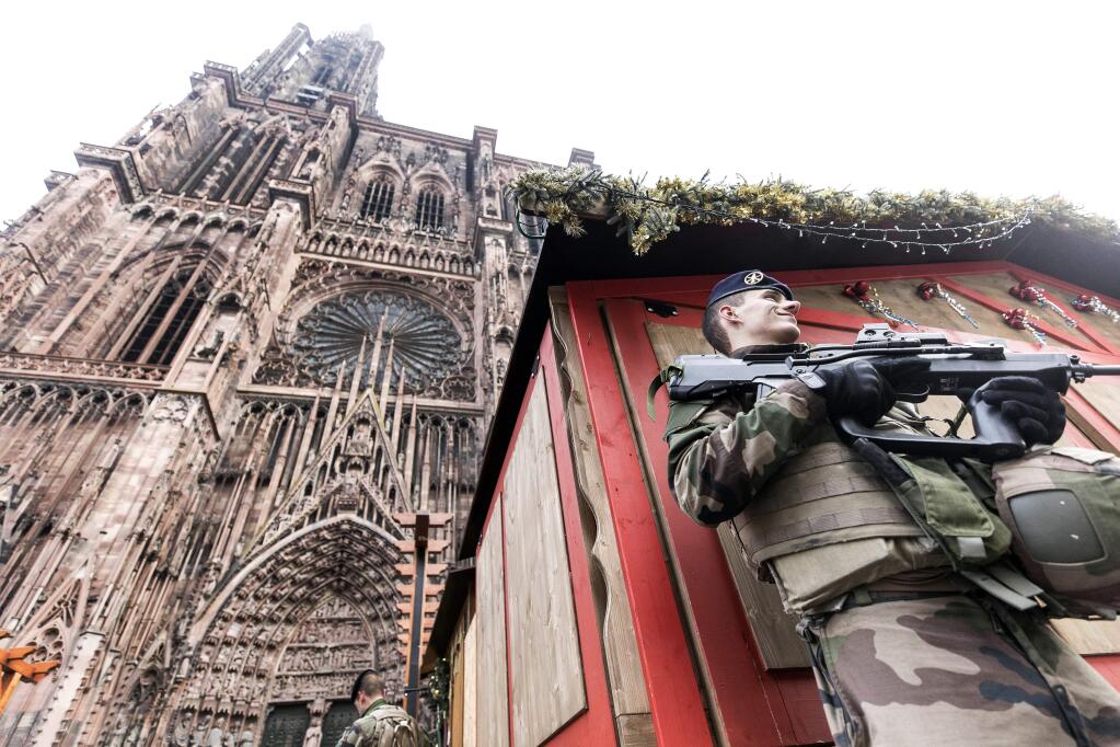 French soldier of France's anti-terror 'Vigipirate' plan, dubbed 'Operation Sentinelle' patrols next to Notre-Dame cathedral of Strasbourg, seen in background, following a shooting in the city of Strasbourg, eastern France, Wednesday, Dec. 12, 2018. A man who had been flagged as a possible extremist sprayed gunfire near the city of Strasbourg's famous Christmas market Tuesday, killing three people, wounding 12 and sparking a massive manhunt. France immediately raised its terror alert level. (AP Photo/Jean Francois Badias)