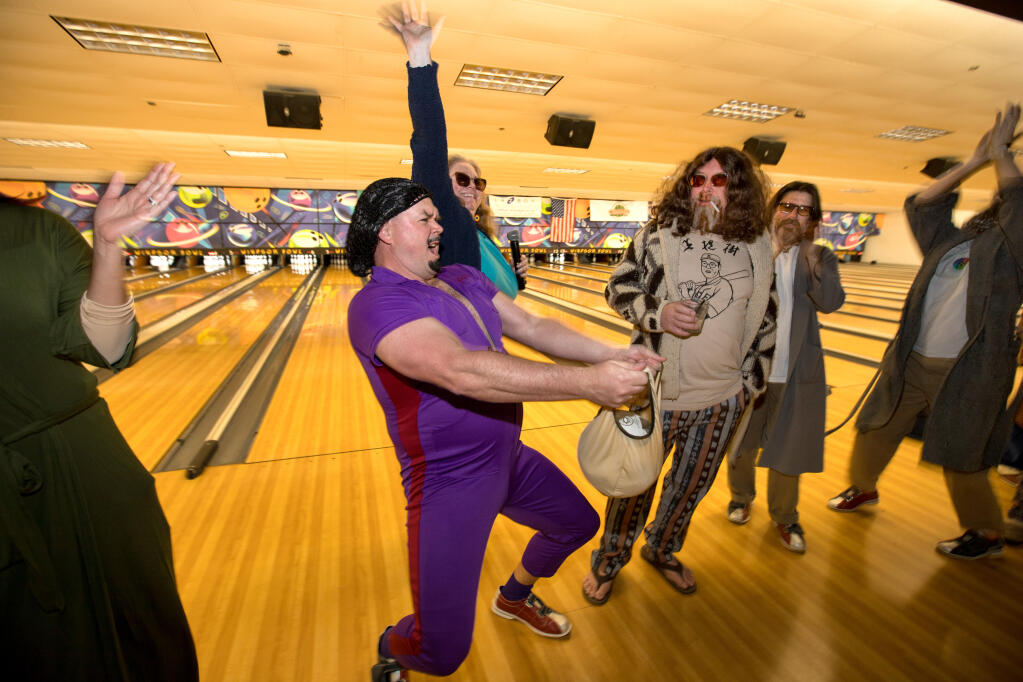 Tim Saunders, of Healdsburg, center left, dressed as character Jesus Quintana from the movie “The Big Lebowski,” is cheered as he is announced in a costume contest he went on to win, by AVFilm's Executive Director, Kathryn Hecht, back (arm raised) as other contestants watch, including Jim Boardman, of Jimtown,  center right, dressed as The Dude, during a "Big LeBOWLski" AVFilm benefit event at Windsor Bowling Center, Monday, Jan. 23, 2023, in Windsor. (Darryl Bush/For The Press Democrat)