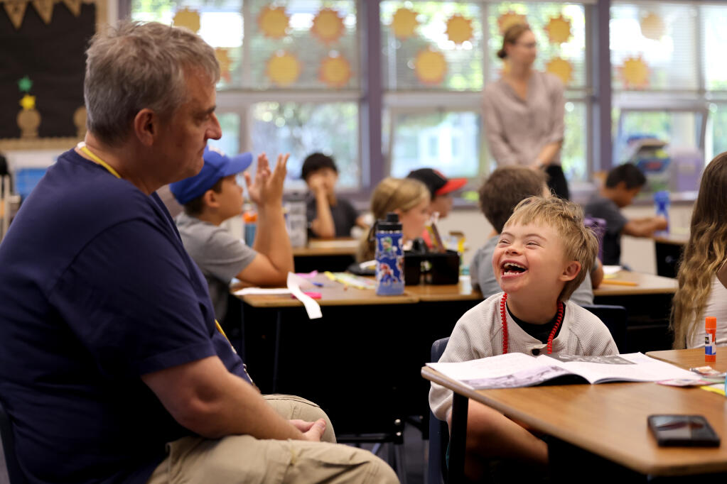 In the 2017-18 school year, California had one of the lowest inclusion rates for students with disabilities in the country. Third grader James O'Leary, 9, smiles at his aide Anthony Carrillo, a behavior technician, during class at Madrone Elementary School in Santa Rosa, Wednesday, Sept. 13, 2023. (Beth Schlanker / The Press Democrat)