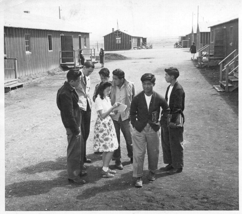 Bill Hosokawa / UC Berkeley, Bancroft LibraryStudents from Heart Mountain high school meet in this campus scene from 1943. Classes were housed in tar paper-covered barracks-style buildings originally designed as living quarters for evacuees.