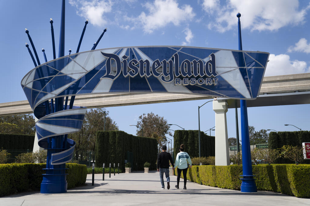 FILE - In this March 9, 2021, file photo, two visitors enter Disneyland Resort in Anaheim, Calif. (AP Photo/Jae C. Hong, File)