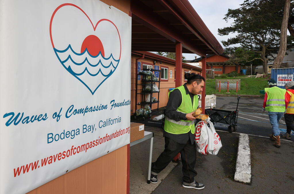 Waves of Compassion Foundation volunteer brings groceries out to a client’s vehicle in Bodega Bay, Wednesday, Feb. 7, 2024. (Christopher Chung / The Press Democrat)