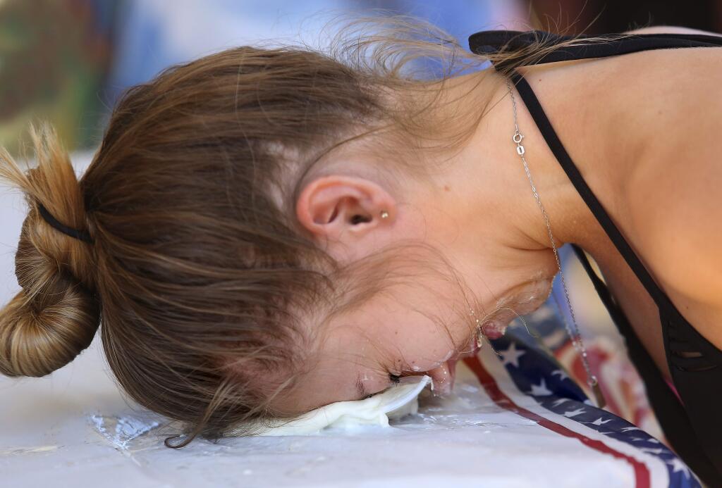 Hollis Wellington, 15, of Los Gatos uses her head to break apart the plastic container to win the ice cream eating contest at the Big Rocky Games at the Monte Rio Beach on Saturday. (John Burgess/The Press Democrat)