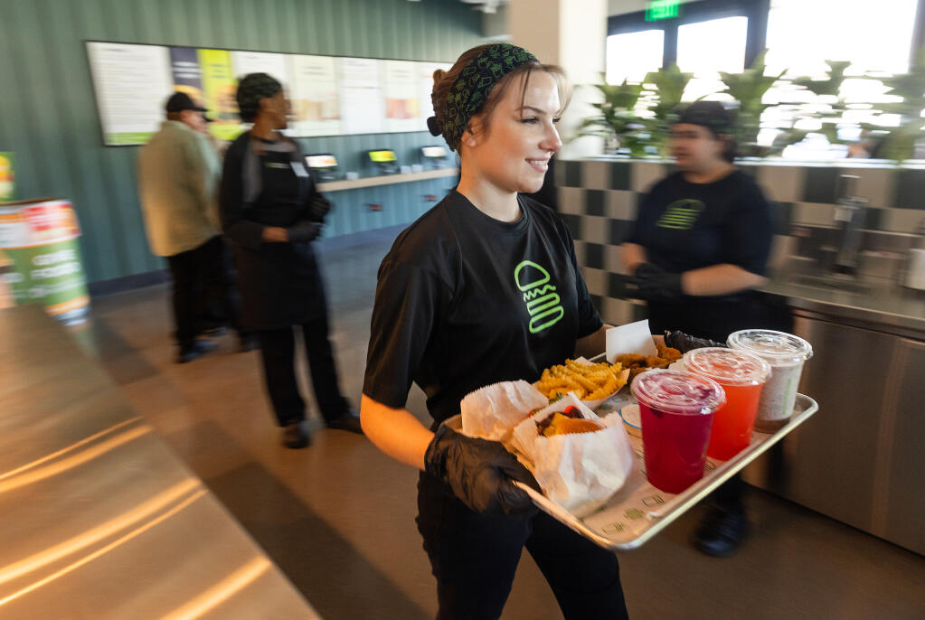 New trainee Elie Woehrle delivers an order to a table at the first Shake Shack in Santa Rosa’s Montgomery Village, Wednesday, Feb. 28, 2024. (John Burgess / The Press Democrat)