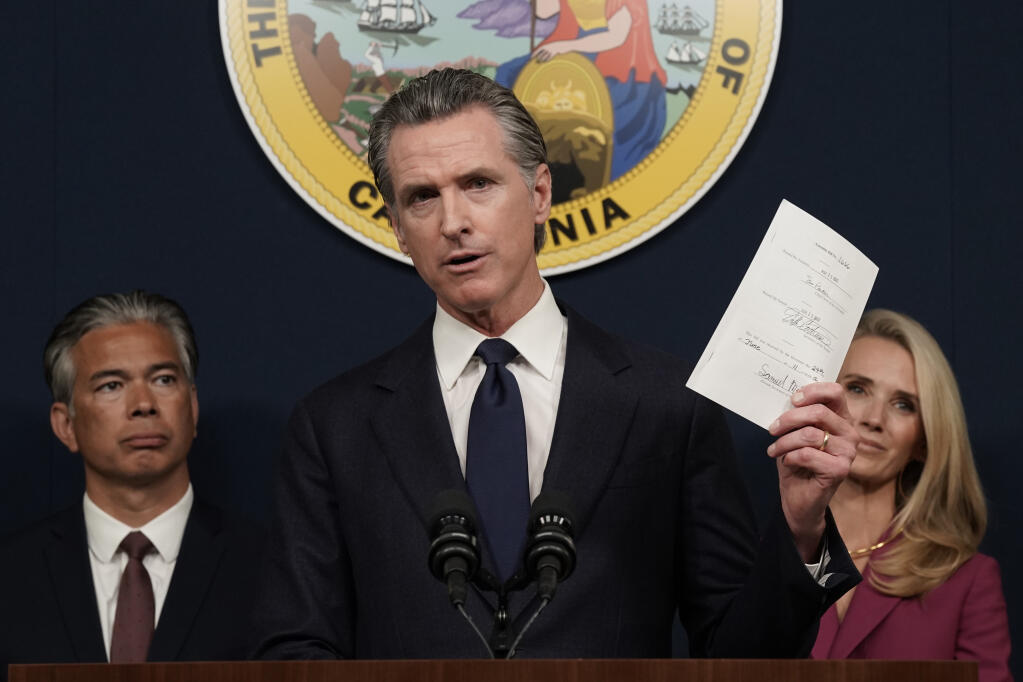 California Gov. Gavin Newsom displays a bill he just signed that shields abortion providers and volunteers in California from civil judgments from out-of-state courts during a news conference in Sacramento, Calif., Friday, June 24, 2022. Newsom angrily denounced the Supreme Court decision to overturn Roe v. Wade. (AP Photo/Rich Pedroncelli)
