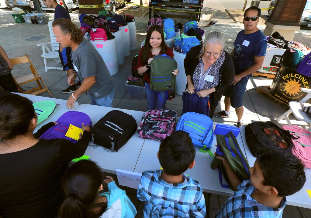 Volunteers hand out backpacks filled with school supplies to needy children at the Redwood Gospel Mission's City Kids North County Festival on the Windsor Town Green on Saturday. (photo by John Burgess/The Press Democrat)