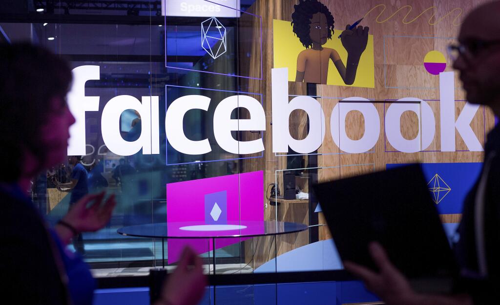 FILE - In this April 18, 2017, file photo, conference workers speak in front of a demo booth at Facebook's annual F8 developer conference in San Jose, Calif. Facebook said Thursday, Jan. 11, 2018, that it is tweaking what people see to make their time on it more “meaningful.” The changes come as Facebook faces criticism that social media can make people feel depressed and isolated. (AP Photo/Noah Berger, File)