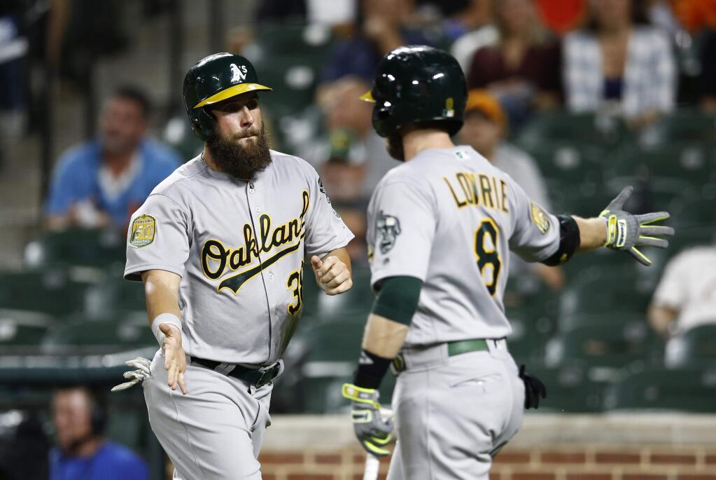 The Oakland Athletics' Nick Martini, left, high-fives teammate Jed Lowrie after scoring on Matt Chapman's single in the third inning against the Baltimore Orioles, Wednesday, Sept. 12, 2018, in Baltimore. (AP Photo/Patrick Semansky)