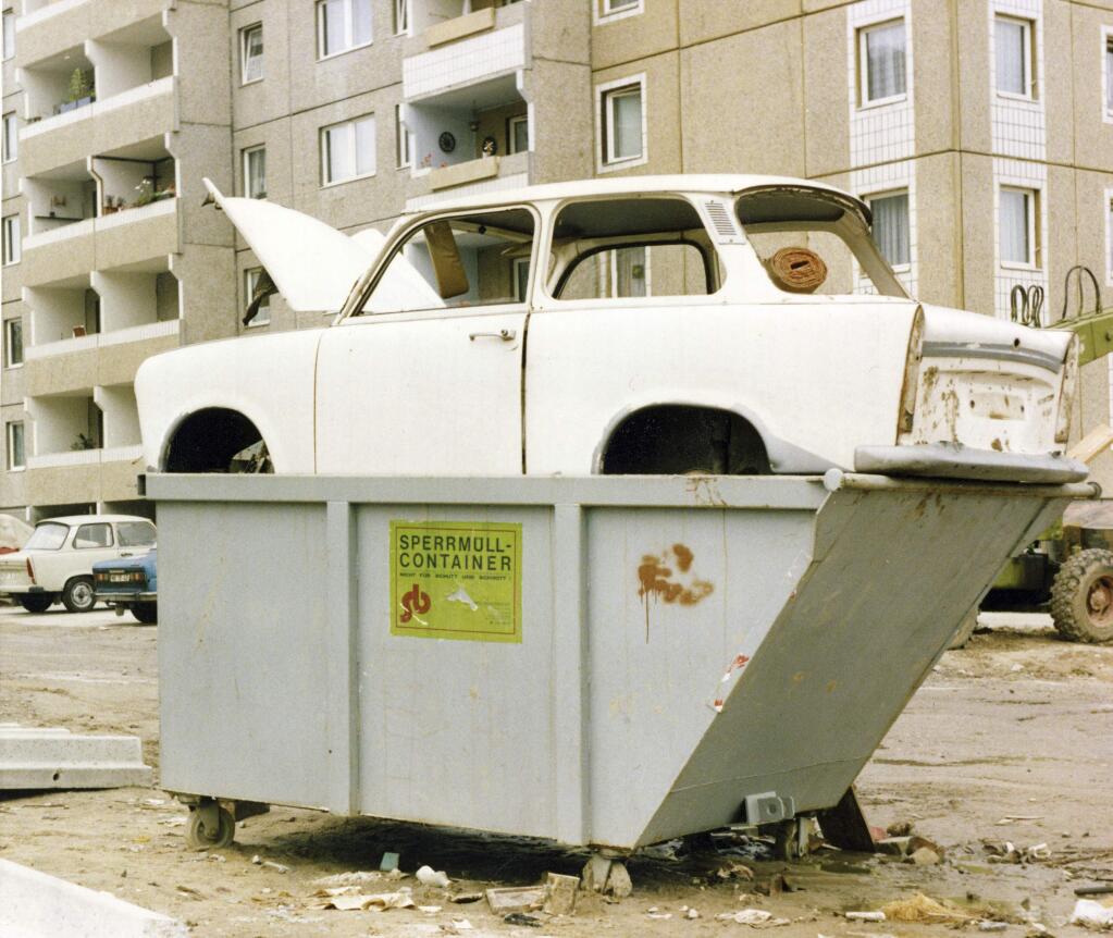 FILE - In this July 12, 1990, file photo, the body of scrapped and stripped Trabant car sit on top of a bulky garbage container at a residential area in former East Berlin, Germany. The former two stroke, two cylinder dream of the once Socialist East Germany now finds itself used as art objects, but mostly is disposed illegally at open places or just left to rot at the side of a road. The abrupt fall of the Wall in 1989 and lightning speed that reunification took place took everyone by surprise at the time and was a shock to the system for some 16 million East Germans. Unrealistic expectations combined with other factors have helped lead to today's discontent, providing fertile ground for the far-right. (AP Photo/Hans Werner Oertel, File)