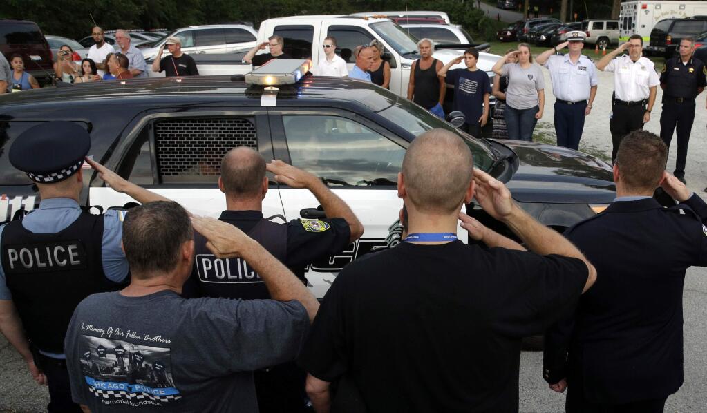 Officers salute as the family of slain Fox Lake police officer Lt. Joe Gliniewicz leave after a vigil at Lakefront Park to honor him, Wednesday, Sept. 2, 2015, in Fox Lake, Ill. Gliniewicz was shot and killed Tuesday while pursuing a group of suspicious men. Authorities broadened the hunt Wednesday for the suspects wanted in the fatal shooting. (AP Photo/Nam Y. Huh)