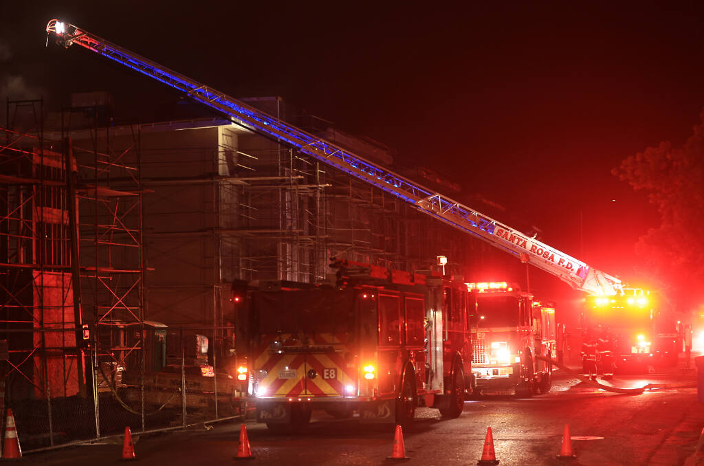 Santa Rosa's Station 2 truck company extended their aerial ladder to the roof of the partially completed Pullman Lofts apartment complex on Wilson and West Ninth streets in Santa Rosa, Friday, Feb. 4, 2022, as firefighters check for extension of a fire that broke out on the first floor. (Kent Porter / The Press Democrat)