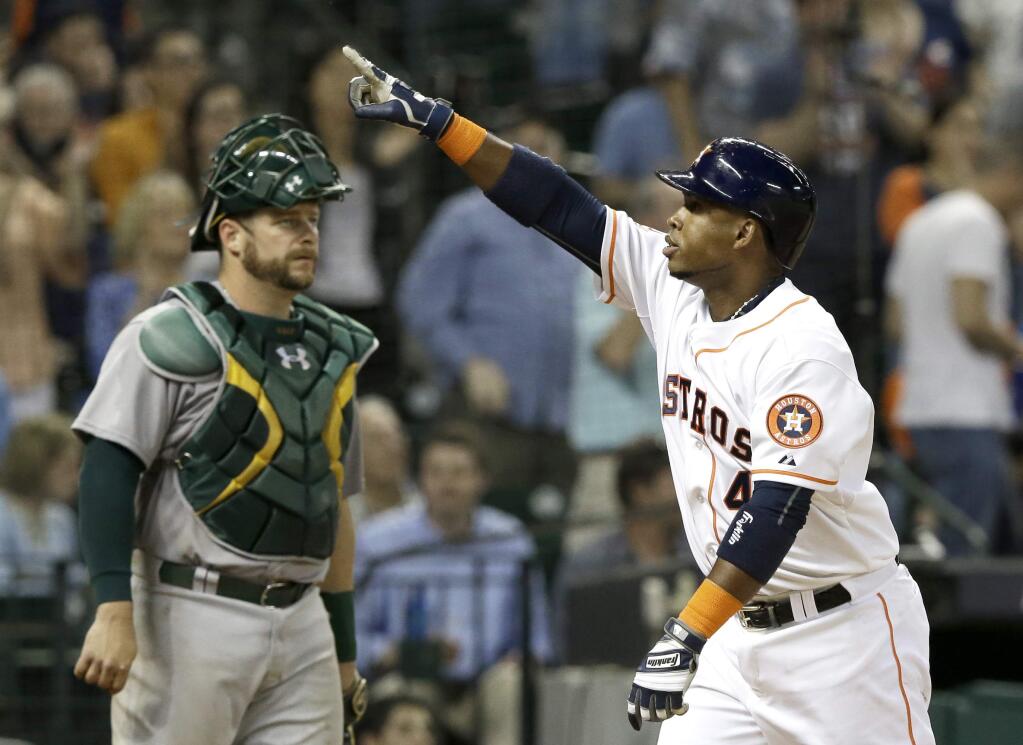 Houston Astros' Luis Valbuena, right, points to the stands after crossing the plate on a solo home run as Oakland Athletics catcher Stephen Vogt looks to the mound in the seventh inning of a game Wednesday, April 15, 2015, in Houston. (AP Photo/Pat Sullivan)